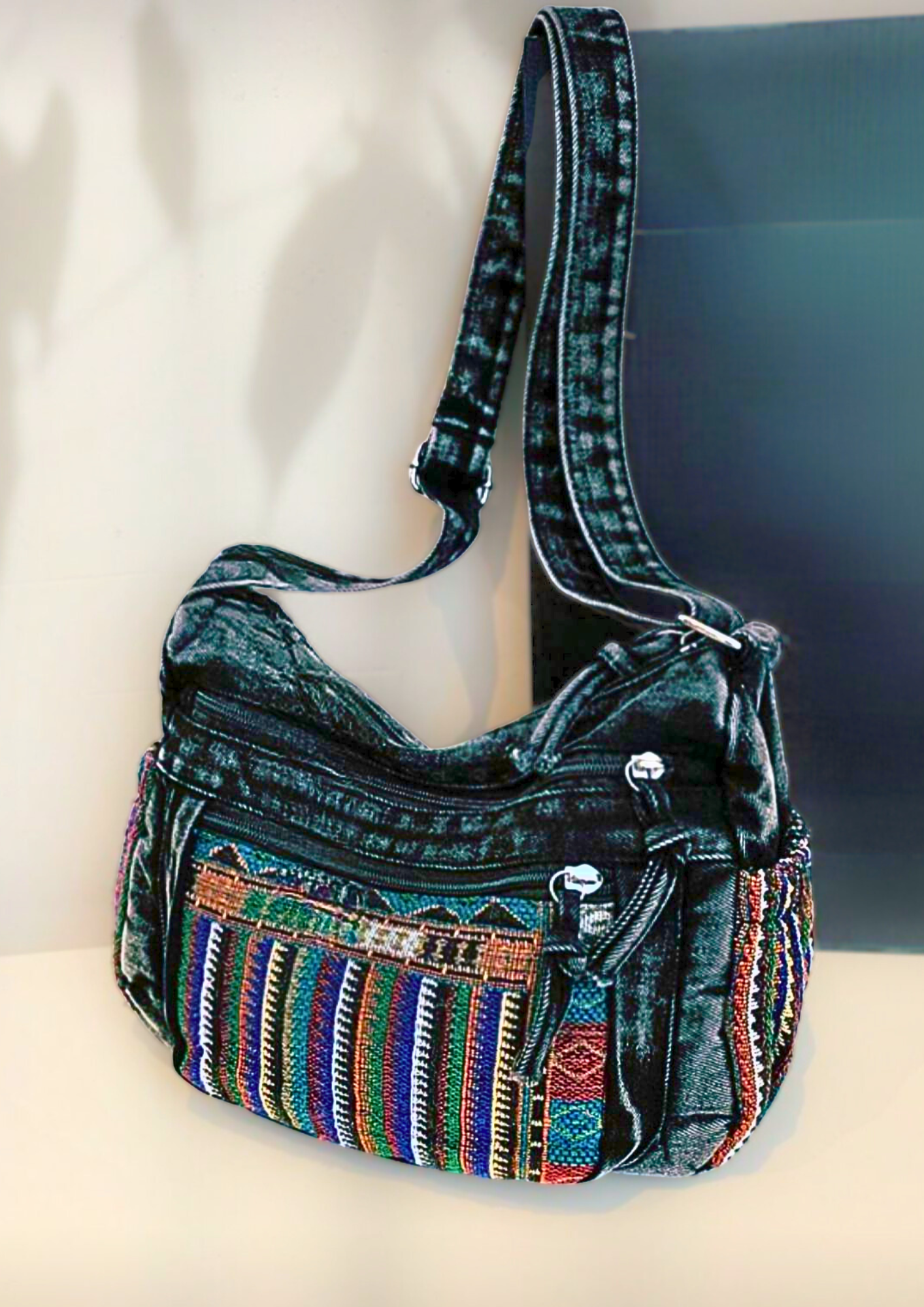 Bolsa transversal preta com bolso frontal em tecido artesanal colorido e alça longa.