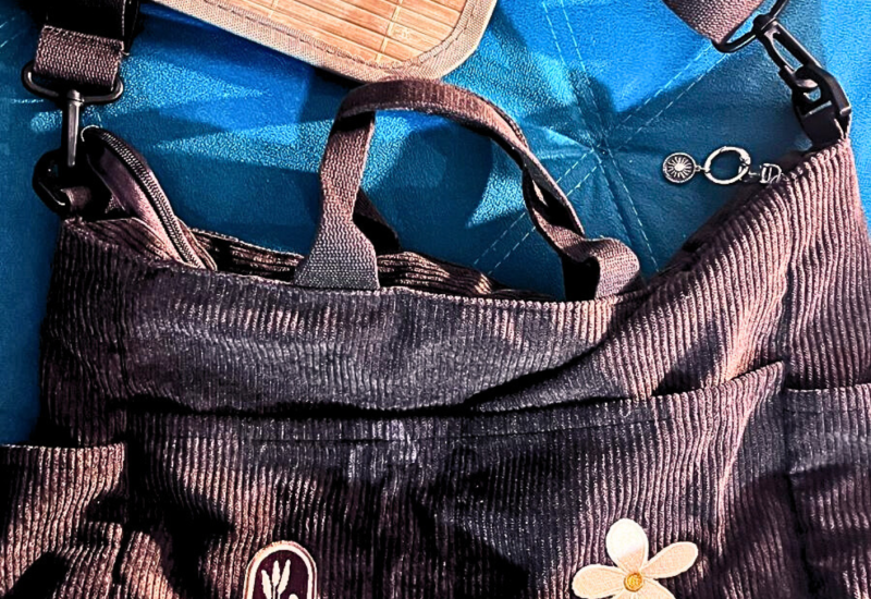 Bolsa marrom em veludo cotelê com alça dupla e aplicação frontal.