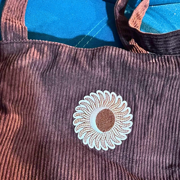 Bolsa marrom em veludo cotelê com aplicação bordada de flor.