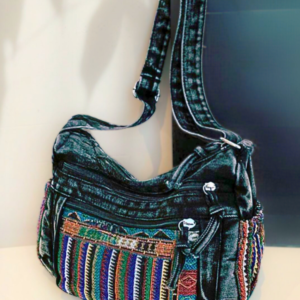 Bolsa transversal preta com bolso frontal em tecido artesanal colorido e alça longa.